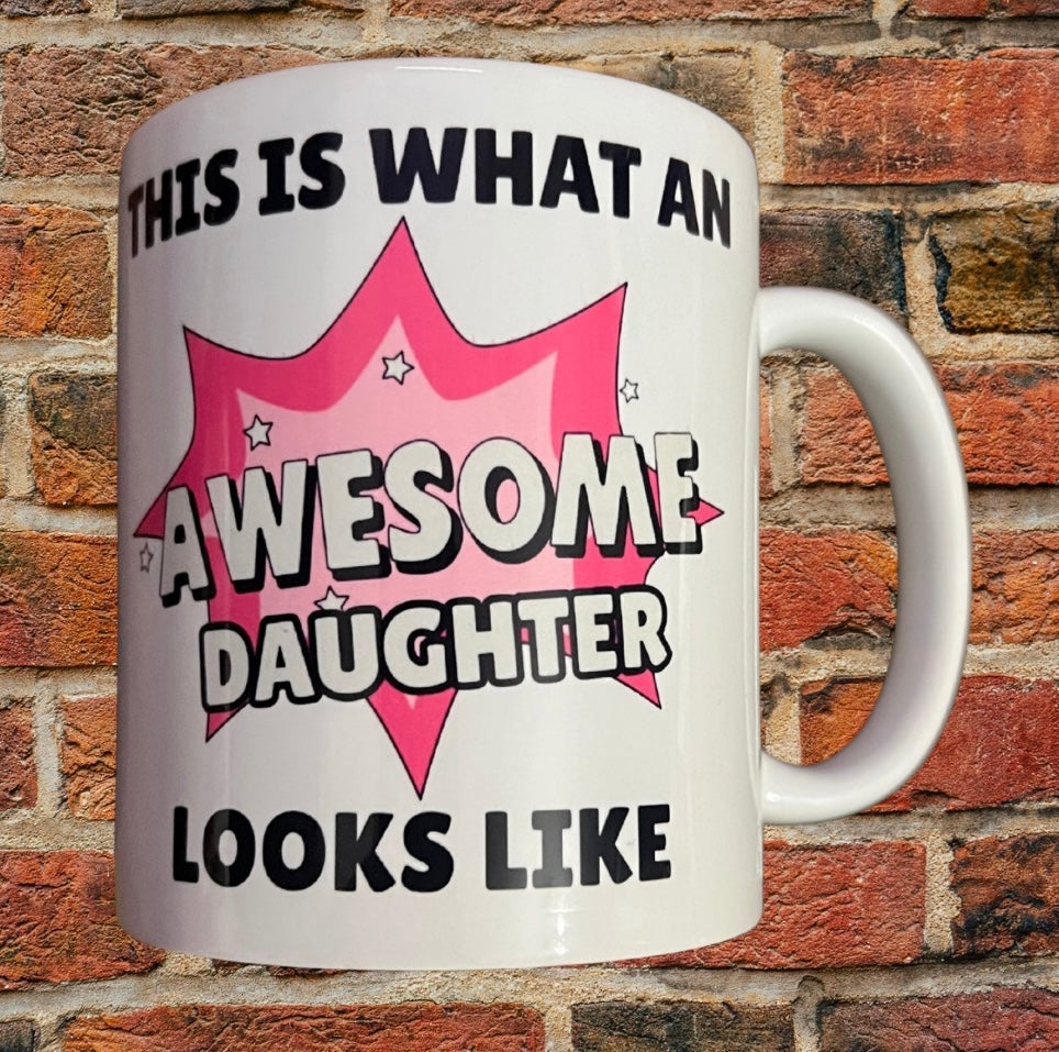 Awesome Daughter Mug Gift with bold pink comic-style design and text 'This is what an awesome daughter looks like' on white ceramic 11oz mug.