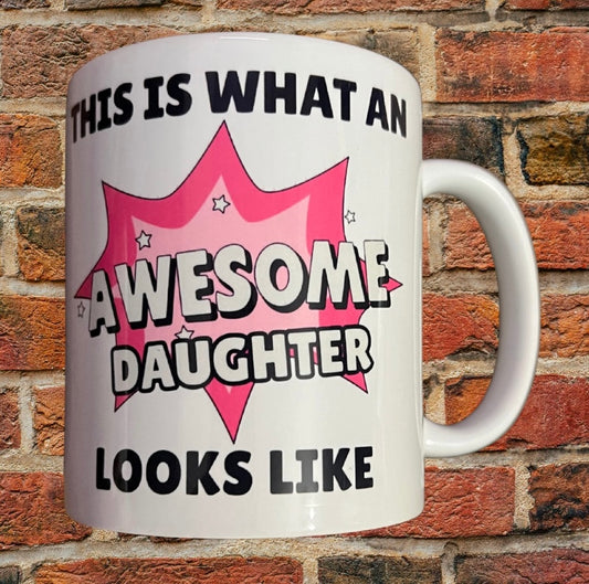 Awesome Daughter Mug Gift with bold pink comic-style design and text 'This is what an awesome daughter looks like' on white ceramic 11oz mug.